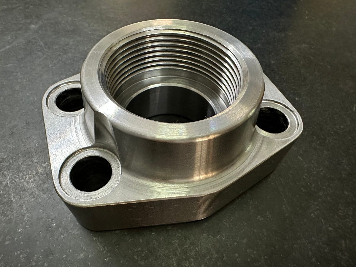 Precision machined stainless steel component with threaded bore and flanged mounting face for pump and seal assemblies